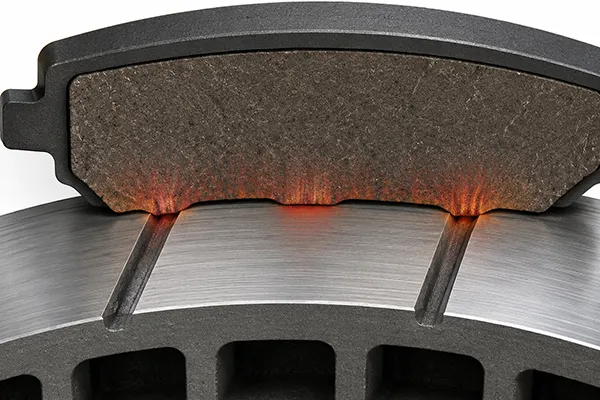 Cross-section diagram of a brake pad contacting a slotted rotor surface